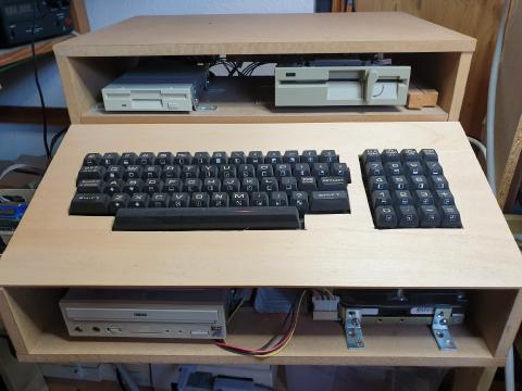 A wooden case with a PET keyboard and two PC disk drives, and a CD drive below the keyboard